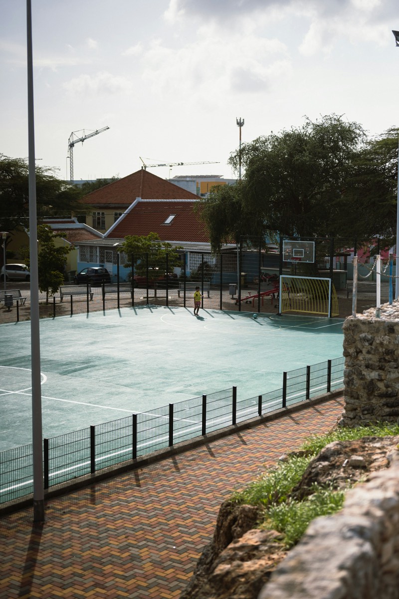 An empty marked court behind a stone wall, goals at either end