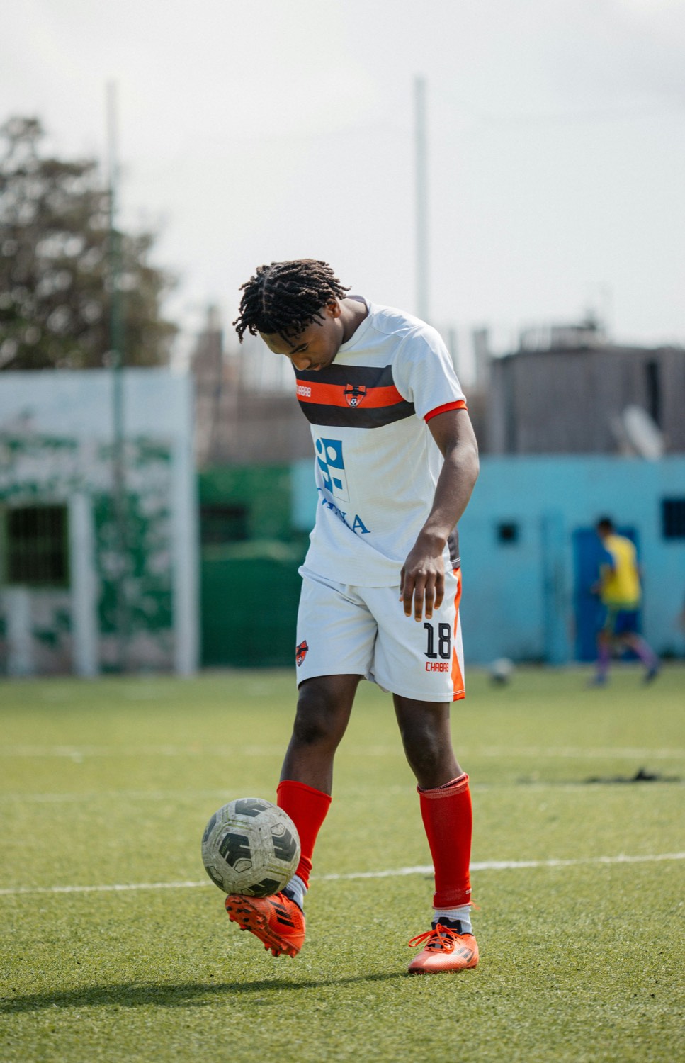 A player in a numbered shirt keeping the ball up on the touchline