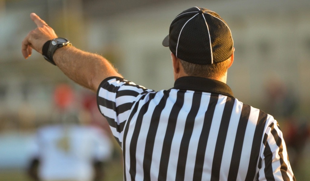 A referee in a striped shirt signalling a decision