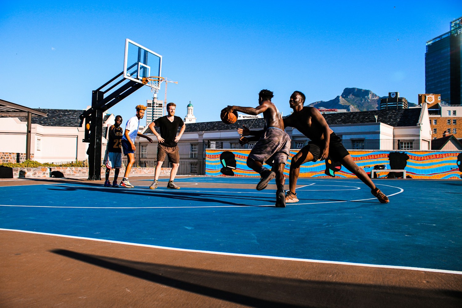 A game on a blue outdoor court with the city and the mountain behind